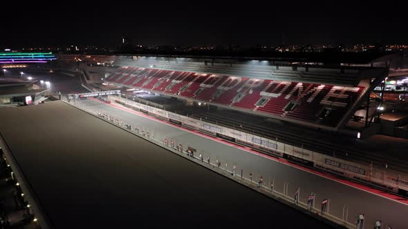 Aerial view of Dubai Autodrome on straight, grand stand, racing during night endurance competition