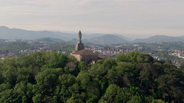 Statue monument and majestic view of San Sebastian and sandy beaches, ascending aerial view alt