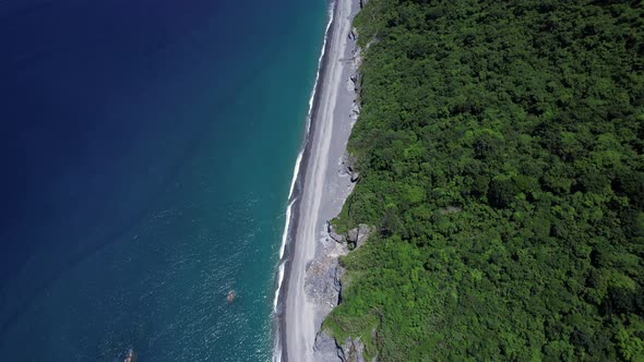 Tropical beach covered in fallen boulders from gradual cliff-side erosion on the Eastern coast of Ta alt