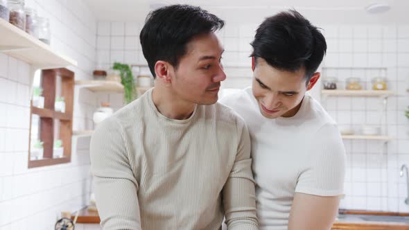 Asia gay couple using tablet and preparing the breakfast, sandwich vegetable on table in kitchen.