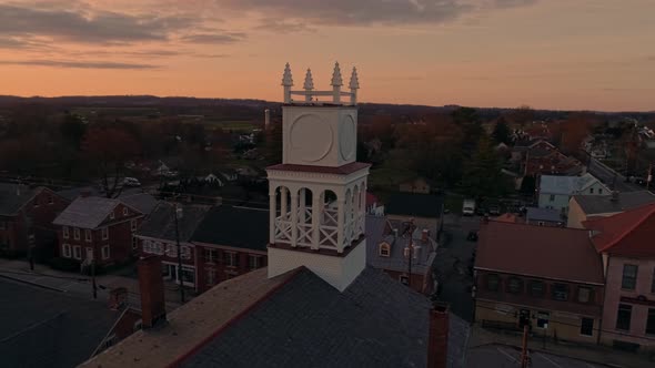 Drone Circling View of a Small Town and a Steeple at Sunrise as it gets Ready to Break the Horizon alt