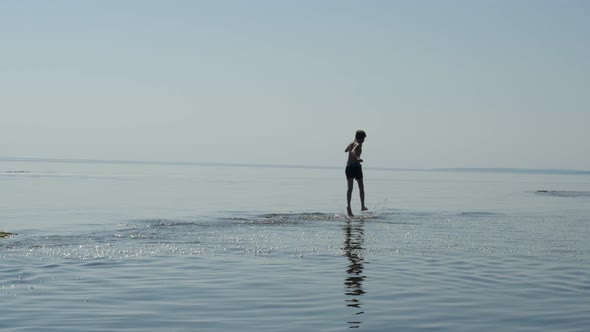 Silhouette of Cheerful Teen Boy Jogging Along Sea Beach