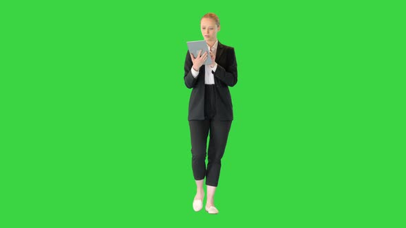 Beautiful Young Business Woman Walking and Using Digital Tablet on a Green Screen Chroma Key alt