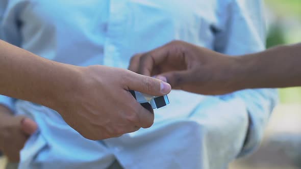 Caucasian male proposing cigarette to black friend alt