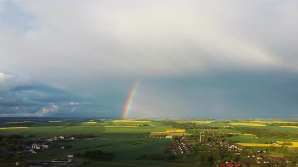 The Rainbow Over Agriculture Landscape Many Fields of Yellow Rapeseed Aerial View 4K alt