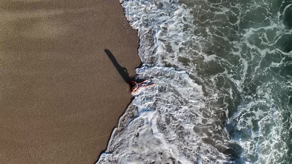 A young girl happily fights with the waves aerial view 4 K alt