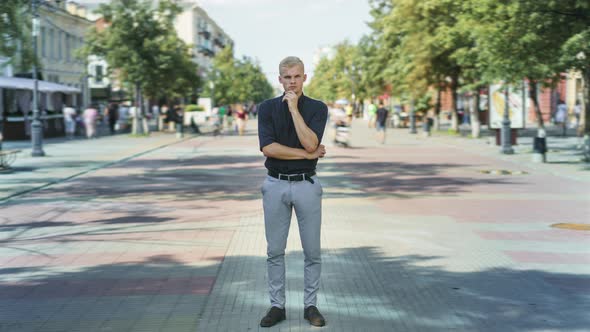 Time Lapse of Attractive Blond Guy Standing Outdoors in Busy Street with Pensive Expression and alt
