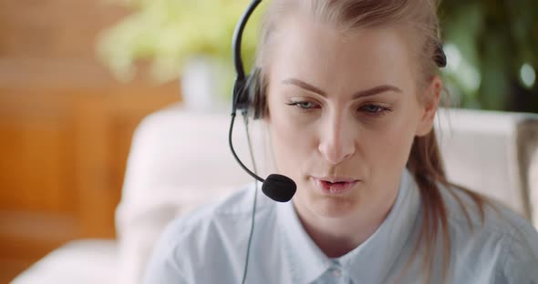 Sales Representative in Headset Speaking To Client and Making Video Conference Call on Laptop alt