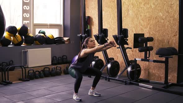 Attractive Slim Brunette Girl Wearing Dryfit Sportswear Doing Squats in the Gym Without Any alt