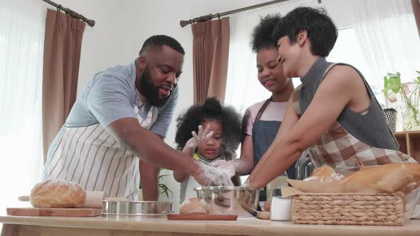 Happy African American family thresh flour together for cookies in the kitchen at home