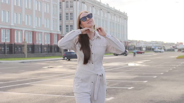 Beautiful Young Girl with Glasses Walks Through the City and Looks Around