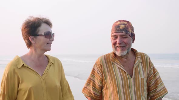 Senior couple walking on the beach and talking, steadicam shot