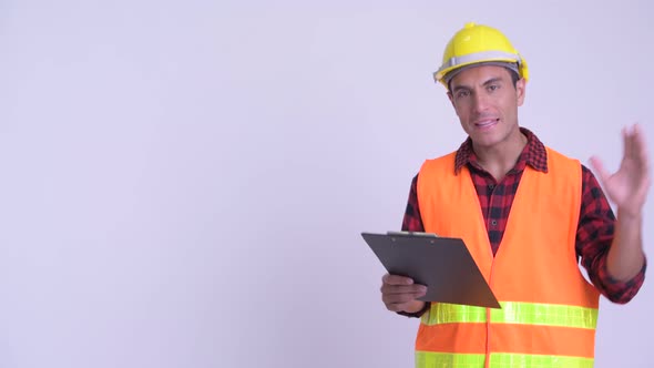 Young Happy Hispanic Man Construction Worker Presenting with Blackboard and Making Mistake