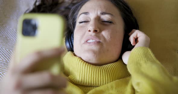 Authentic shot of woman on the bed listening to music and singing