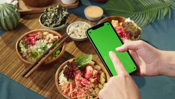 Hawaiian Poke Bowls Holding Smartphone with Chroma Green Screen Closeup alt