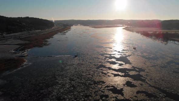 Sunbeam On Melting Ice On River Reflection On Surface Sunset Pull Back Aerial alt