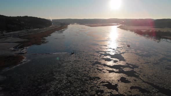 Sunbeam On Melting Ice On River Reflection On Surface Sunset Pull Back Aerial