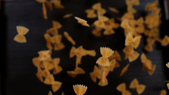 Farfalle pasta flying up and hanging in the air on a black background alt