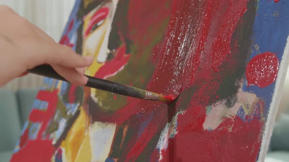 Close Up Of A Hand's Girl Holding Paintbrush And Painting A Girl's Face On The Canvas alt