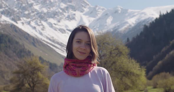 Portrait of Young Woman Smiling on Background of Snowy Mountains
