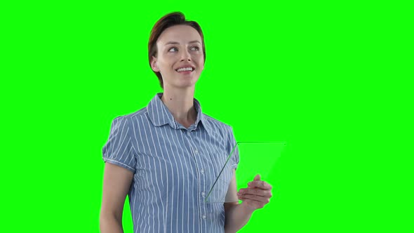 Caucasian woman holding a transparent screen on green background