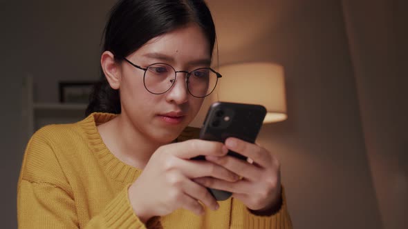 Young woman using a smartphone chatting and shopping online from home During COVID-19 pandemic. alt