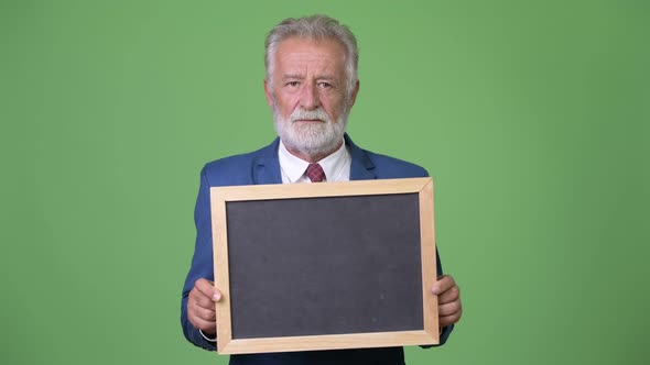 Handsome Senior Bearded Businessman Against Green Background alt