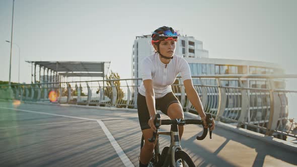 Girl in Sportswear and Protective Helmet is Riding Trekking Bike Downhill Along Bridge Surrounded By alt
