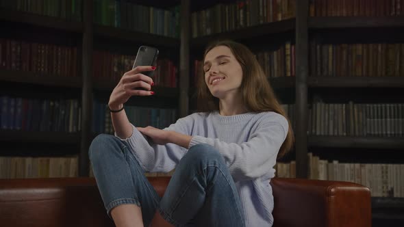 Young Adult Caucasian Woman Student Taking Selfie on Her Smart Phone Indoors in Slow Motion alt