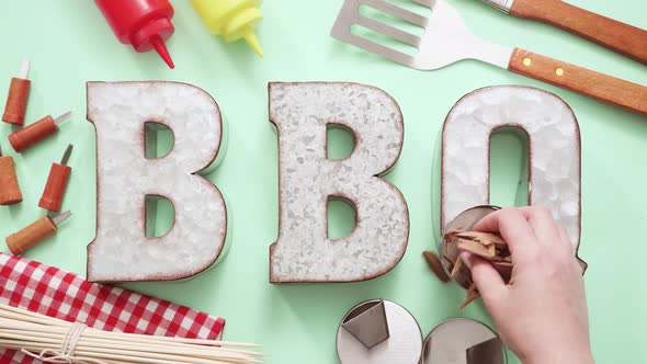 Metal BBQ sign with grilling tools on blue background. alt