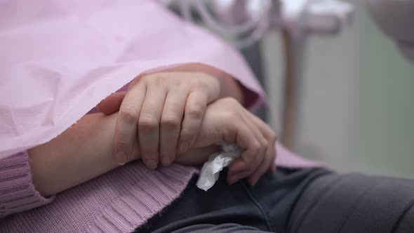 Closeup Hands of Caucasian Woman Sitting in Dental Chair in Hospital alt