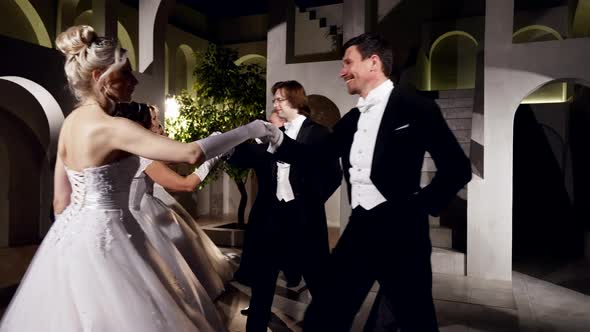 Beautiful Women in White Gorgeous Dresses and Men in Black Suits are Dancing in Ballroom alt
