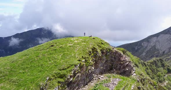 Aerial drone view of a man taking a selfie dronie on a hill top in Montenegro. alt
