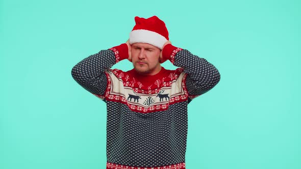 Man in Christmas Sweater Covering Ears and Gesturing No Avoiding Advice Ignoring Unpleasant Noise alt