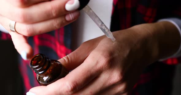 Anonymous woman applies aromatic essential cosmetic oil to her hands, alt