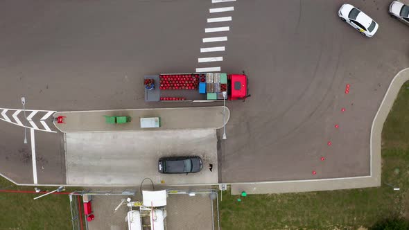 A car with red gas cylinders at a gas station. Top view from drone