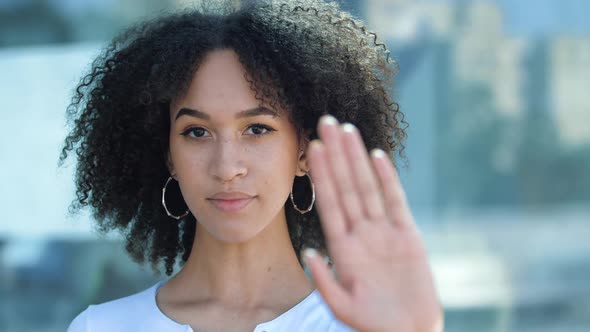 Serious African American Girl Covers Herself with Her Palm, Confidently Shows Prohibitory Gesture alt