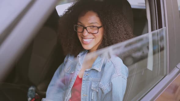 Happy Young Smiling African American Woman Black Haired Driver in Glasses Sitting in New Brown Car