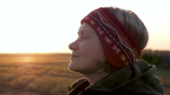Mature Old Woman Standing Outdoors At Sunset Takes A Deep Breath To Relax alt