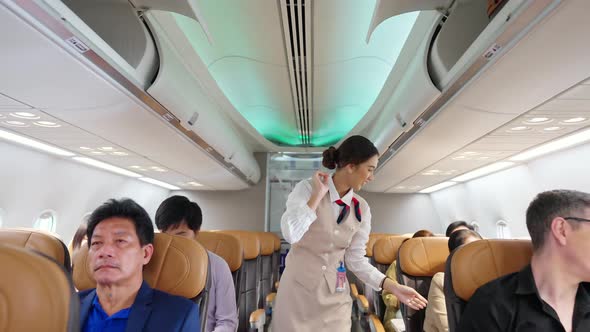 4K Asian woman flight attendant closing luggage compartment before aircraft take off runway. alt