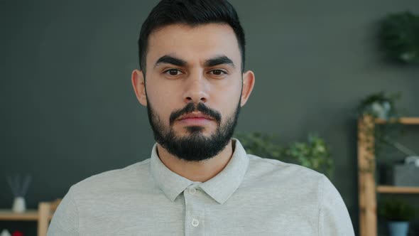 Slow Motion Portrait of Serious Middle Eastern Man Looking at Camera at Home alt