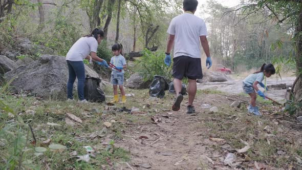 Group of Asian volunteer families collecting garbage and plastic by the river. alt