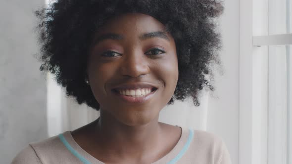 Closeup Portrait African Young Woman with Afro Hair Beautiful Face Standing Indoor Smile Look at alt