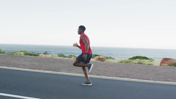 African american man exercising outdoors running on a coastal road alt