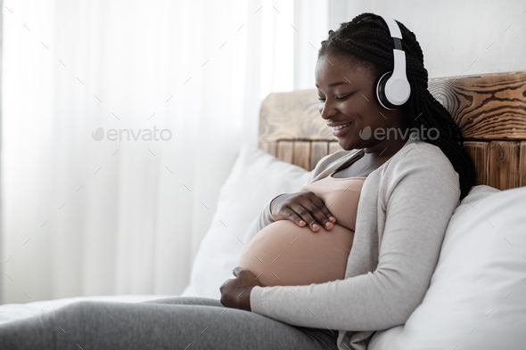 Pregnant Woman Holding Headphones Near Belly, Playing Melody To Baby In  Womb Stock Photo by Prostock-studio