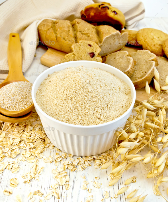 Flour oat in white bowl with bran in spoon on board - Stock Photo - Images