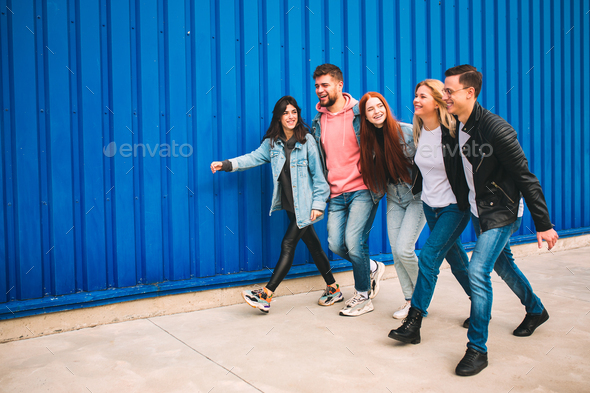 Group of four young diverse friends in jeanse outfit look carefree, young and happy on city's