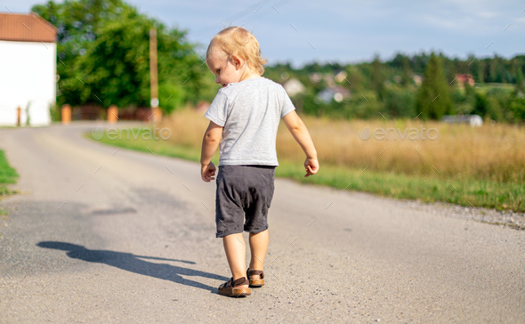 Child boy walking alone on road at countryside Stock Photo by leszekglasner