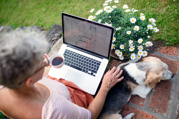 Top view of senior woman architect with laptop working outdoors in garden, home office concept.