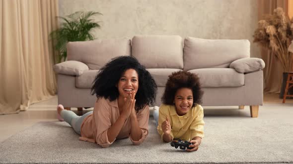 Little African American Girl Plays Game on Wireless Joystick and Rejoices Victory alt